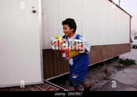 7. Februar 2006; Pahokee, FL, USA; Junior Ruiz, 11, betritt sein Haus mit Geschenken, die Familien zur Verfügung gestellt von Kirchen bei der Weihnachtsfeier von Larry Wright, der Pahokee, für Familien von Ushers Trailer Park in Pahokee Dienstag organisiert. Bewohner des Parks waren ohne Strom für 101 Tage nachdem Hurrikan Wilma Bereich getroffen. Drei Kirchen aus dem Bereich brachte Geschenke, Essen und clot Stockfoto