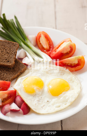 Zwei Spiegeleier mit gelben Eigelb und Gemüse Stockfoto