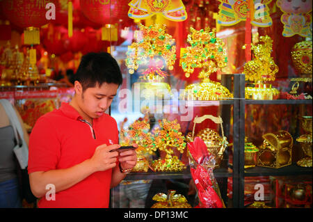 Kuala Lumpur, MYS. 5. Januar 2014. Ein Mann prüft sein Handy in einem Laden verkaufen Chinese New Year Dekorationen in Kuala Lumpur, Malaysia, Sonntag, 5. Januar 2014. Das diesjährige chinesische Neujahrsfest fällt am 31. Januar 2014. Joshua Paul/NurPhoto/ZUMAPRESS.com/Alamy © Live-Nachrichten Stockfoto