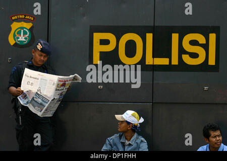 1. Mai 2006; Jakarta, Indonesien; Eine Polizei mit seinem Gewehr liest Lokalzeitung während stützte sich auf ein gepanzertes Fahrzeug. Tausende von Arbeitern aus verschiedenen Regionen sammelten für die Kennzeichnung der internationalen Arbeiter Tag Ð May Day. Neben Protest der Revisionen, Arbeitsrecht verlangen sie auch Regierung Maifeiertag als nationaler Feiertag zu erklären. Polizei bei der Demonstration gehalten wachsames Auge für Stockfoto