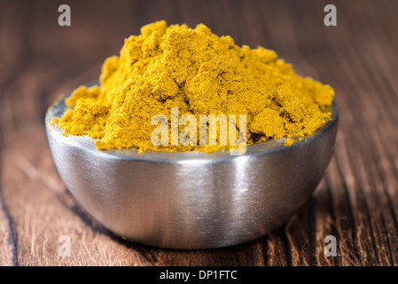 Schüssel mit Curry-Pulver auf dunklem Holz Stockfoto