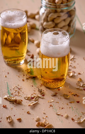 Bier mit Erdnüssen auf alten Holztisch Stockfoto