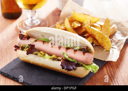 Gourmet Hotdog auf Schiefer Board mit rustikalen Pommes frites Stockfoto