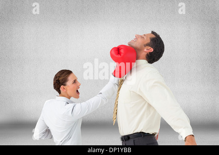 Zusammengesetztes Bild der Geschäftsfrau schlagen einen Geschäftsmann mit Boxhandschuhen Stockfoto