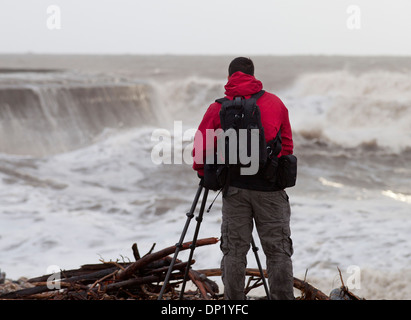 Ein Fotograf macht Fotos von Winterwellen, die über die Maiskolben in Lyme Regis. Stockfoto