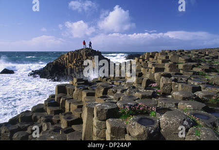 Die Leute stehen auf dem sechseckigen Basaltsäulen der Giant's Causeway, County Antrim, Nordirland. Stockfoto