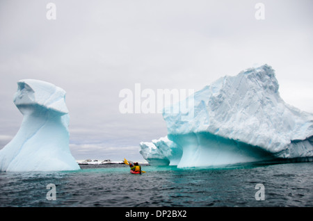 Antarktis - Kajakfahrer in einem Tandem kayak vorbei ein Eisberg, der langsam an Hydrurga Felsen an zwei hummock Insel kippen. Die Region ist bekannt als Favorit für die seeleoparden (Hydrurga leptonyx). Stockfoto