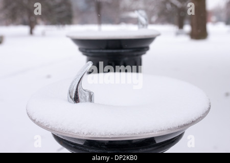 Den letzten Schneefall umfasst Bäume, Parkbänke und Trinkbrunnen im Victoria Park. Stockfoto