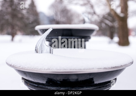 Den letzten Schneefall umfasst Bäume, Parkbänke und Trinkbrunnen im Victoria Park. Stockfoto