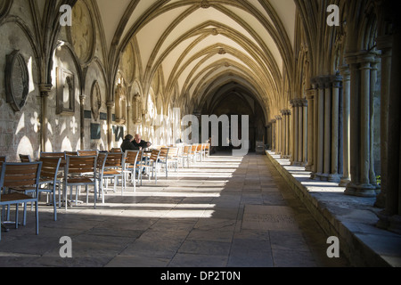 Älteres Ehepaar saß am Tisch in der Klausur bei Salisbury Kathedrale Wiltshire UK mit Schatten Besetzung über Boden und Wände Stockfoto