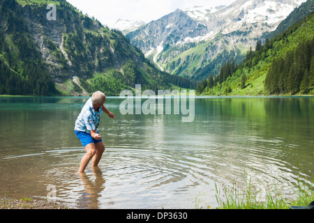 Reifer Mann skipping Stones auf See Vilsalpsee, Tannheimer Tal, Österreich Stockfoto