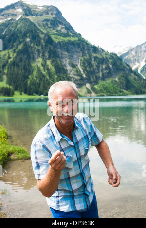 Porträt des reifen Mannes skipping Stones auf See Vilsalpsee, Tannheimer Tal, Österreich Stockfoto