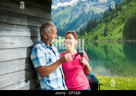 Reifer Mann mit Blume, Reife Frau, neben Gebäude am See Vilsalpsee, Tannheimer Tal, Österreich Stockfoto