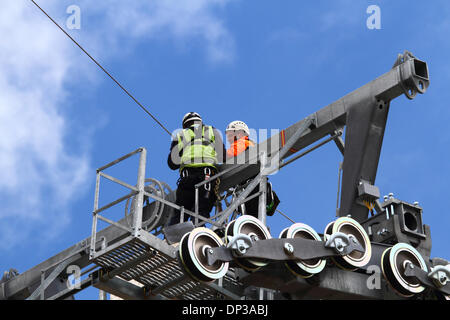 La Paz, Bolivien. 7. Januar 2014. Techniker installiert ein synthetisches Lichtkabel (das mit dem Hubschrauber durchgeführt worden ist) in Position zwischen Führungsrollen an einem Hochspannungsmast. Dies ist die erste Stufe des Prozesses die endgültige Stahlseil zu installieren, die die Gondeln für die neue Seilbahn führt / Gondelbahn, die derzeit im Bau, die Städte La Paz und El Alto zu verknüpfen. Drei separate Routen sollen im Rahmen eines ehrgeizigen Projekts um Verkehrsstaus zu entlasten. Das System wird von der österreichischen Firma Doppelmayr zu einem Preis von $ 234,6 Millionen von der bolivianischen Regierung finanzierten gebaut. Stockfoto