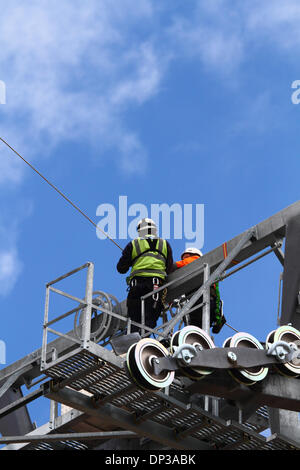 La Paz, Bolivien. 7. Januar 2014. Techniker installieren ein synthetisches Lichtkabel (das mit dem Hubschrauber durchgeführt worden ist) in Position zwischen Führungsrollen an einem Hochspannungsmast. Dies ist die erste Stufe des Prozesses die endgültige Stahlseil zu installieren, die die Gondeln für die neue Seilbahn führt / Gondelbahn, die derzeit im Bau, die Städte La Paz und El Alto zu verknüpfen. Drei separate Routen sollen im Rahmen eines ehrgeizigen Projekts um Verkehrsstaus zu entlasten. Das System wird von der österreichischen Firma Doppelmayr zu einem Preis von $ 234,6 Millionen von der bolivianischen Regierung finanzierten gebaut. Stockfoto