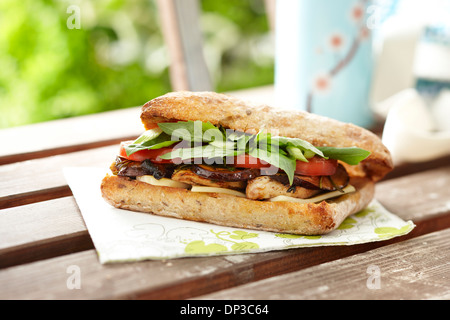 Gegrillte Hähnchen und Portobello Mushroom Sandwich mit Basilikum, Tomaten, und Käse, Focaccia Vollkornbrot, auf Tisch Stockfoto