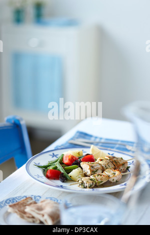 Griechischen Abendessen mit Chicken-Souvlaki, grüne Bohnen, Tomaten, Kartoffeln, Pita-Brot und Zitronenscheibe auf Tisch Stockfoto