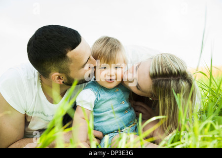 Porträt von Mutter und Vater küssen Baby Tochter Wangen, Mannheim, Baden-Württemberg, Deutschland Stockfoto