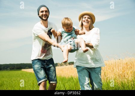 Eltern, die Swinging Baby Tochter von Agrarbereich, Mannheim, Baden-Württemberg, Deutschland Stockfoto