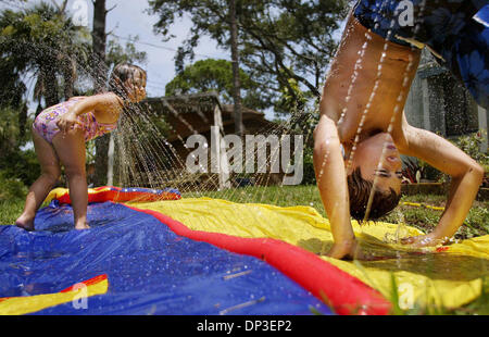 30. Juni 2006; Fort Pierce, FL, USA; Delaney Slattery, 3, trinkt aus der Gischt des Slip-n'slide, ebenso wie ihr Bruder, Jacob Slattery, 8, ein Frontflip am Freitag in ihrem Vorgarten in Fort Pierce.   Obligatorische Credit: Foto von Amanda Voisard/Palm Beach Post/ZUMA Press. (©) Copyright 2006 von Palm Beach Post Stockfoto