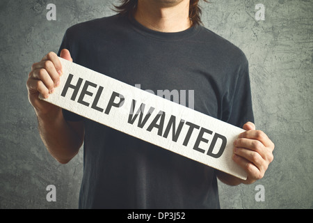 Legerer Mann bat um Hilfe, die weiße Tafel mit Help Wanted Titel halten. Stockfoto