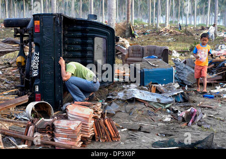 19. Juli 2006; Ciamis, West-Java, Indonesien; Indonesische Tsunami-Überlebende Ade Kusmawan bereinigt sein beschädigtes Auto das von Montages Tsunami mitgerissen, wie ihn sein Sohn in Pangandaran Strand verbindet. Ein Tsunami traf die Küste der indonesischen Insel Java und hat mehr als 550 Leben, verlassen über 600 verletzt, rund 38.000 anderen wurden durch die Katastrophe vertrieben. Ein earthquak Stockfoto