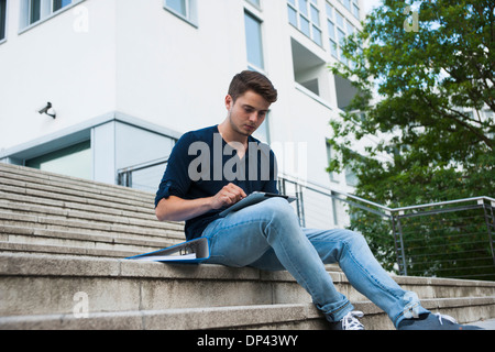 Junger Mann sitzt auf Schritte im Freien, mit Tablet-PC, Deutschland Stockfoto