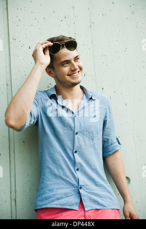 Porträt des jungen Mannes im Freien, halten Sonnenbrillen und Blick auf die Seite, Deutschland Stockfoto