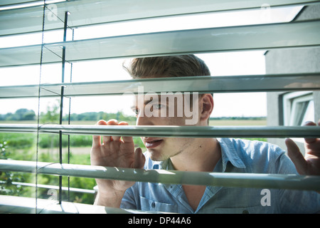 Nahaufnahme des jungen Mannes durch Vorhänge am Fenster, Deutschland Stockfoto