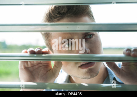 Nahaufnahme des jungen Mannes durch Vorhänge am Fenster, Deutschland Stockfoto