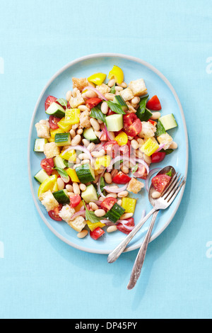 Draufsicht der Brotsalat mit weißen Bohnen, Tomaten, Paprika und Gurken, blauer Hintergrund, Studioaufnahme Stockfoto