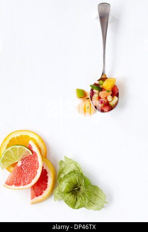 Draufsicht der Zitrusfrucht Gazpacho auf Löffel mit Zitrus-Scheiben und Tomatillo, weißer Hintergrund, Studioaufnahme Stockfoto
