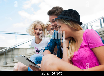Gruppe von Jugendlichen sitzen auf Treppen im freien Blick auf Tablet-PC, Deutschland Stockfoto