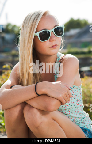 Porträt von Teenager-Mädchen im Freien zu sitzen, das Tragen von Sonnenbrillen und Blick auf die Seite, Deutschland Stockfoto