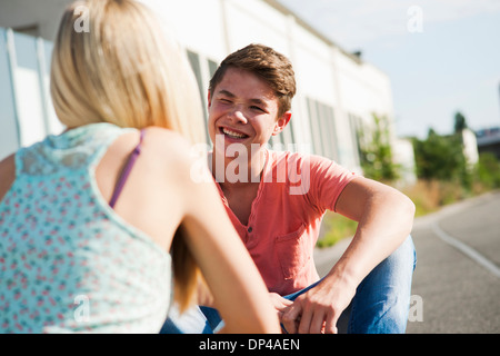 Teenager-Mädchen und Jungen auf der Straße sitzen, reden, Deutschland Stockfoto