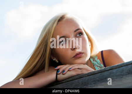 Porträt von Teenager-Mädchen sitzen auf der Bank im Freien, Blick in die Ferne, Deutschland Stockfoto