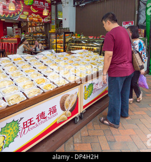 Mann sucht bei Durian Frucht auf Verkauf im Markt Personal in Chinatown, Singapur. Stockfoto