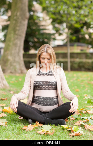 Schwangere Frau sitzen im park Stockfoto