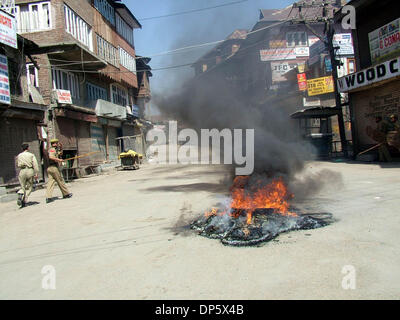 Sep 27, 2006; Srinagar, Kaschmir, Indien; Ein Polizist schaut zu, wie Demonstranten verbrennen Reifen in Srinagar, Sommer in der Hauptstadt des indischen verabreicht Kaschmir. Kaschmir ist ausgebrochen, an den Protesten am Mittwoch, nachdem ein indisches Gericht zum Tode verurteilt, Afzal Guroo, ein Geschäftsmann, der Kashmiri ausgesprochen für den Angriff auf das indische Parlament im Dezember 2001 beteiligt. Obligatorische Credit: Foto von Alta Stockfoto