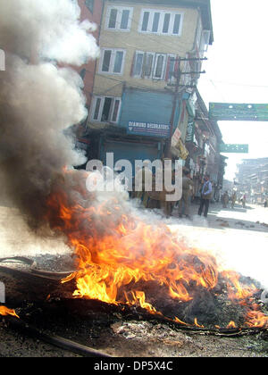 Sep 27, 2006; Srinagar, Kaschmir, Indien; Ein Polizist schaut zu, wie Demonstranten verbrennen Reifen in Srinagar, Sommer in der Hauptstadt des indischen verabreicht Kaschmir. Kaschmir ist ausgebrochen, an den Protesten am Mittwoch, nachdem ein indisches Gericht zum Tode verurteilt, Afzal Guroo, ein Geschäftsmann, der Kashmiri ausgesprochen für den Angriff auf das indische Parlament im Dezember 2001 beteiligt. Obligatorische Credit: Foto von Alta Stockfoto