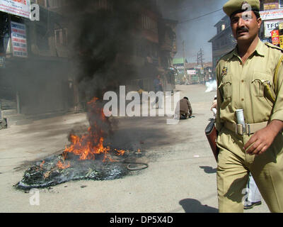 Sep 27, 2006; Srinagar, Kaschmir, Indien; Ein Polizist kommt vorbei, wie Demonstranten verbrennen Reifen in Srinagar, Sommer in der Hauptstadt des indischen verabreicht Kaschmir. Kaschmir ist ausgebrochen, an den Protesten am Mittwoch, nachdem ein indisches Gericht zum Tode verurteilt, Afzal Guroo, ein Geschäftsmann, der Kashmiri ausgesprochen für den Angriff auf das indische Parlament im Dezember 2001 beteiligt. Obligatorische Credit: Foto von Alta Stockfoto