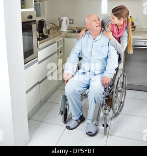 Familie mit älteren Mann im Rollstuhl zu Hause in der Küche Stockfoto