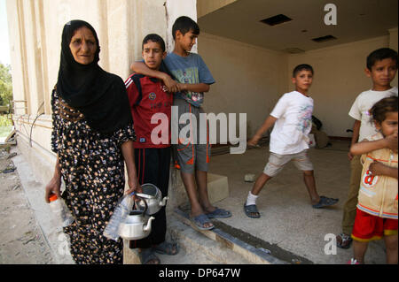 6. Oktober 2006; Bagdad, Irak; Eine irakische Frau sammelt Wasser für ihre Familie vor einem Zimmer in Saddam Husseins persönliches Kino in Bagdads Green Zone. Einige irakische Familien, vertrieben nach der Invasion 2003 suchten Zuflucht in den Überresten von Saddam Husseins persönliches Kino, gebaut, um den ehemaligen irakischen Präsidenten während seiner Herrschaft zu unterhalten. Die Familien befürchten, dass als Eigenschaftswerte in Stockfoto