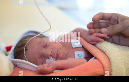 Braunschweig, Deutschland. 7. Januar 2014. Eine Mutter hält die Hand ihres vorzeitigen gelieferten Sohnes liegen in einem Inkubator in einem Raum von der pädiatrischen Intensivstation des Klinikum Braunschweig in Braunschweig, Deutschland, 7. Januar 2014. Die Intensivstation für Kinder inzwischen existiert schon seit 35 Jahren und ist damit der älteste Intensivstation für Frühgeborene und Kinder in Niedersachsen. Foto: Jochen Luebke/Dpa/Alamy Live News Stockfoto