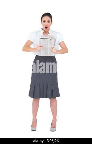 Schockiert stilvolle Geschäftsfrau hält Zeitung Stockfoto