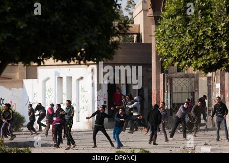 Kairo, Ägypten. 8. Januar 2014. Protestierende Studenten mit Steinen auf Polizisten vor der Azhar-Universität in Kairo, Ägypten, 8. Januar 2014 werfen. Kairo Strafgerichtshof vertagte am Mittwoch die Testversion des gestürzten Präsidenten Mohamed Morsi über Anstiftung zu töten Demonstranten zum 1. Februar wegen des schlechten Wetters, die seinen Transport des Gerichts verhindert das Staatsfernsehen berichtet. Bildnachweis: Cui Xinyu/Xinhua/Alamy Live-Nachrichten Stockfoto