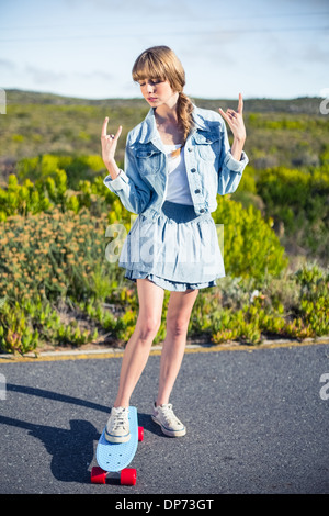 Attraktive blonde machen Rock'n'Roll Handbewegung Stockfoto