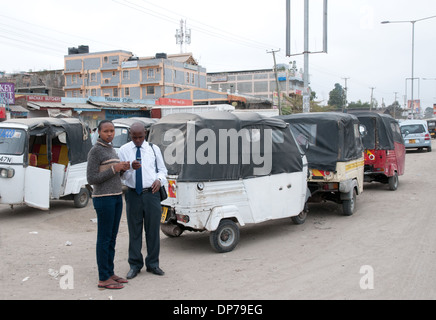 Junge afrikanische paar mit Handy in der Nähe von Tuk Tuk taxis am Kaijado auf Nairobi Namanga Straße Kenia Afrika Stockfoto