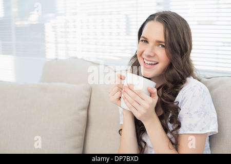 Fröhliche junge Frau im Schlafanzug mit Kaffee Stockfoto