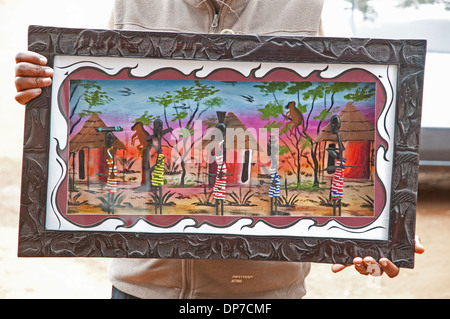 Bunte afrikanische Gemälde in geschnitzten Holzrahmen zeigt Dorf Rondavel Hütten und Frauen in traditioneller Kleidung zum Verkauf Kenia Stockfoto